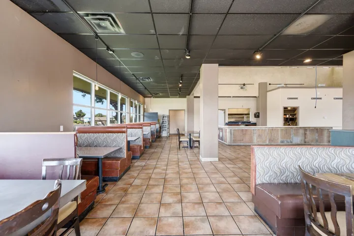 Expansive tile flooring, suspended ceiling with track lighting, multiple large windows, and an integrated counter area