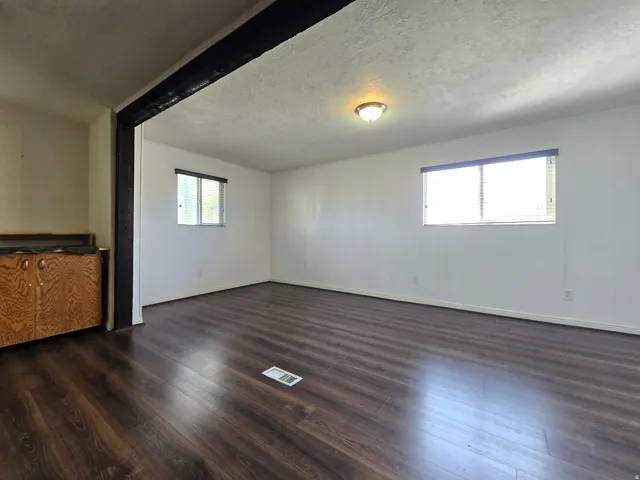 Wood-finish flooring throughout, multiple windows, built-in wooden cabinetry, and overhead lighting