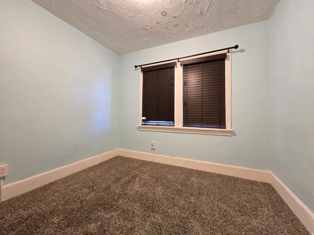 Window with horizontal blinds and an upper rod, light blue wall paint, and gray carpet flooring
