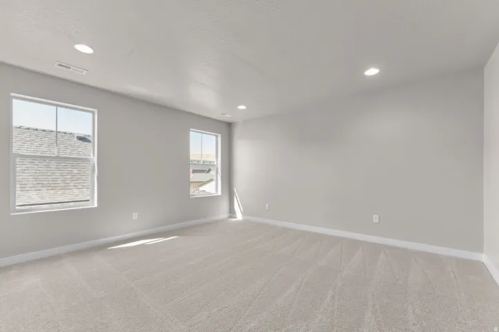 Plush carpet flooring, recessed ceiling lighting, and two windows