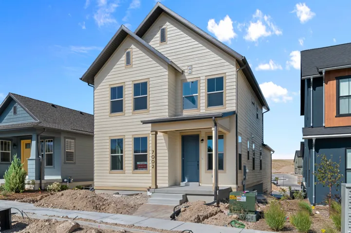 Two-story residence with light-colored horizontal siding, a covered entryway with a blue door, and multiple windows with dark frames