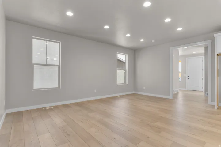 Recessed lighting, wood-finish flooring, light gray wall paint, and white trim