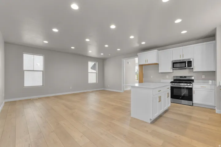 Open concept living space featuring wood-finish flooring, recessed lighting, and multiple windows