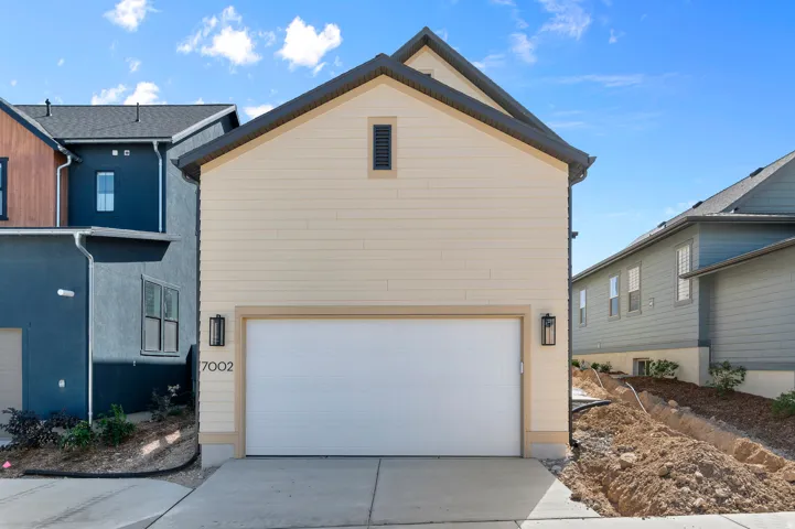 Cream-colored horizontal siding with dark trim, featuring an attached garage with a white door