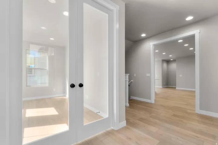 White French doors with matte black hardware, wood-finish flooring, recessed lighting, and light gray wall paint
