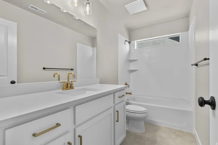 Double vanity with white cabinetry, gold-tone hardware, and integrated sinks