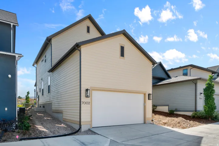 Contemporary exterior featuring a two-car garage, durable siding, and exterior lighting fixtures