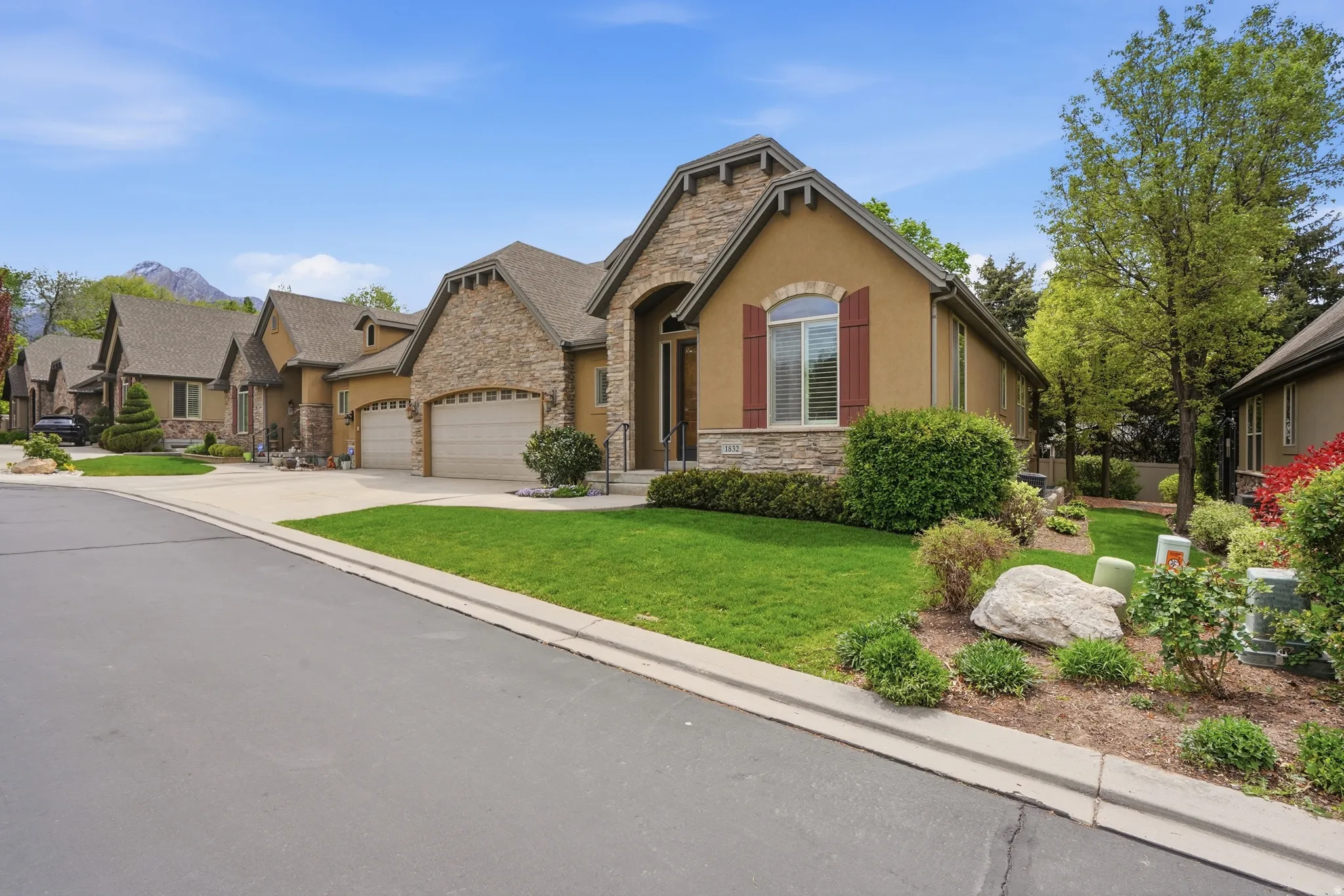 Stone and stucco exterior with multiple gables, arched entry, and window shutters