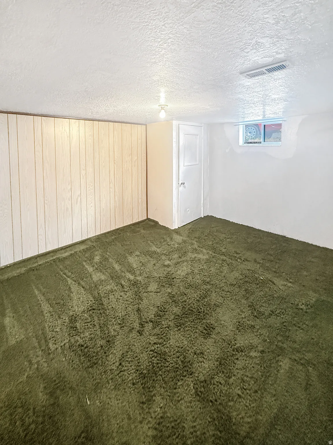 Deep pile green carpeting covers the floor, complementing the white wood paneling and painted walls