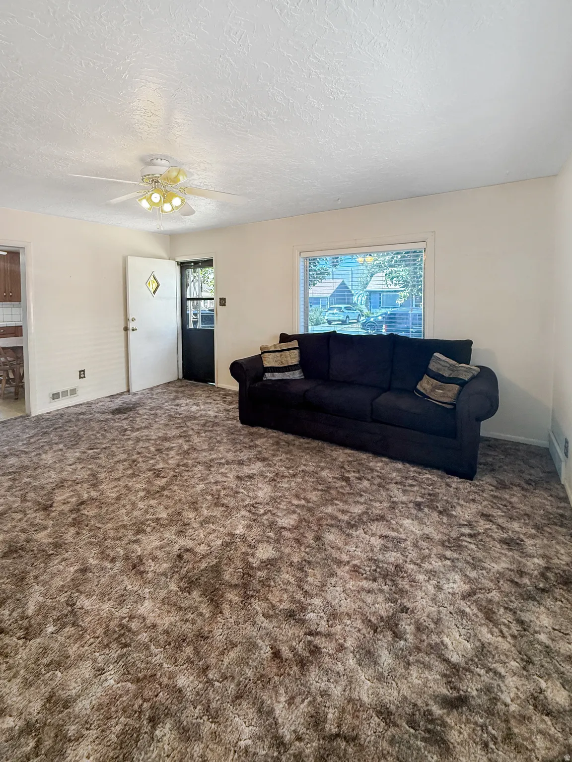 Carpeted living space with a ceiling fan light fixture