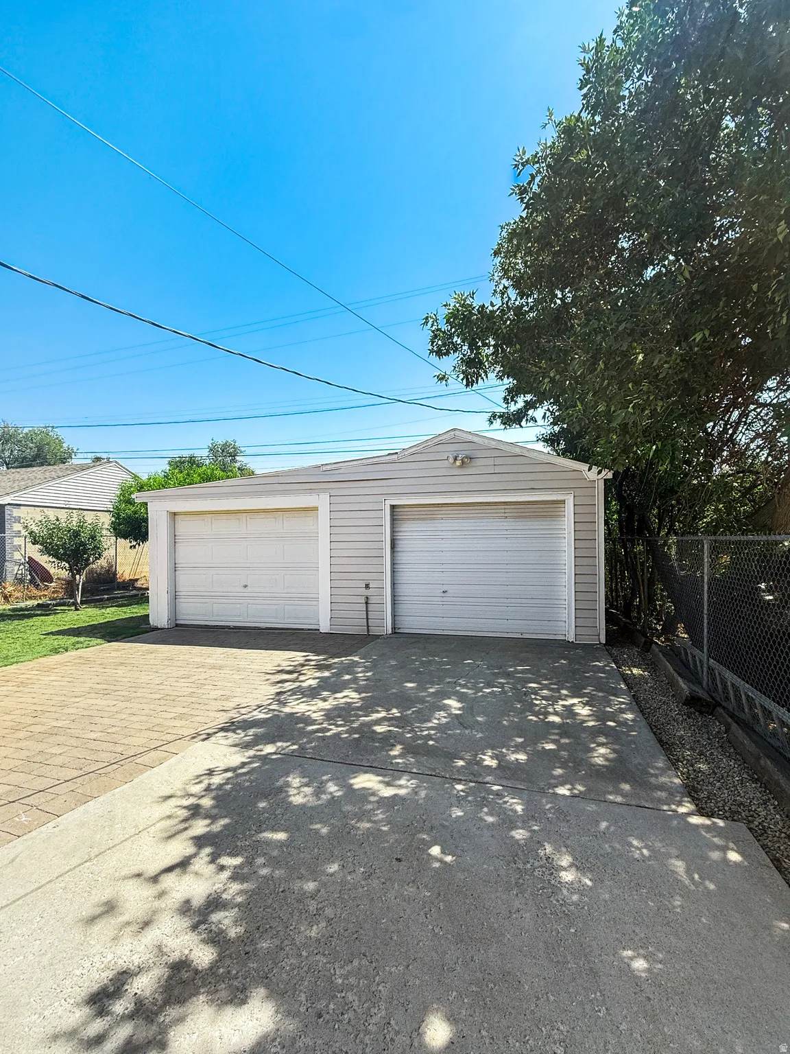 Two-car garage with light-colored siding and white garage doors