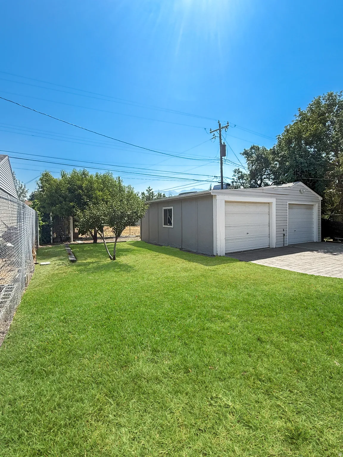 Spacious backyard featuring a lush lawn, established trees, and a detached two-car garage with an additional single-car garage