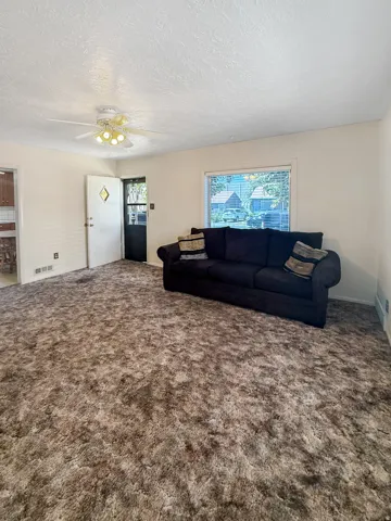 Carpeted living space with a ceiling fan light fixture