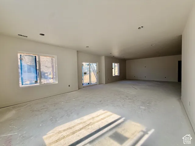 Expansive open-concept space featuring multiple windows, a sliding glass door, recessed lighting, and a neutral wall color