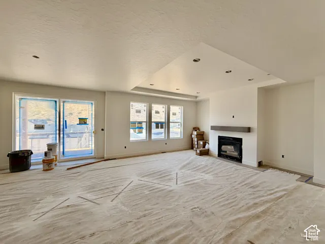 Recessed ceiling lighting, vaulted ceiling, built-in fireplace, wood mantle, and sliding glass doors