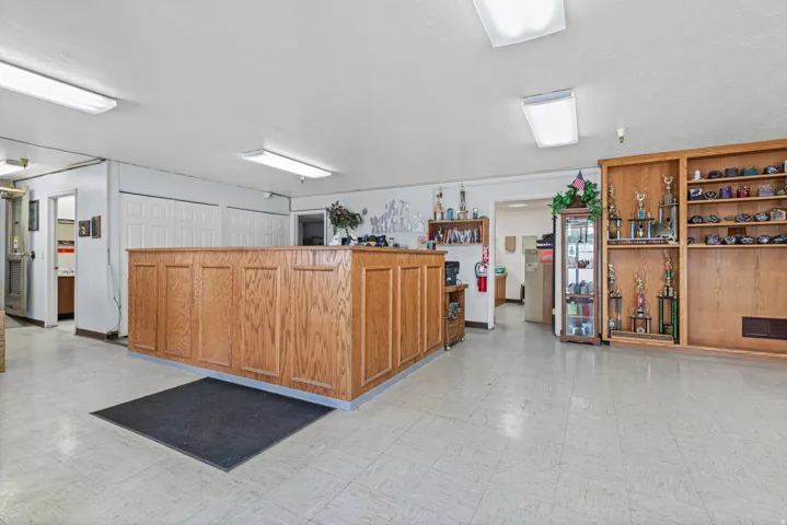 Spacious open area with light-colored flooring, extensive built-in wooden shelving, a large wood-paneled counter, and white double doors