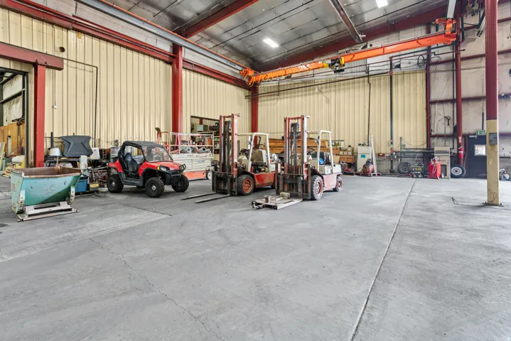 Concrete flooring, structural steel beams, corrugated metal walls, overhead crane system, high ceilings