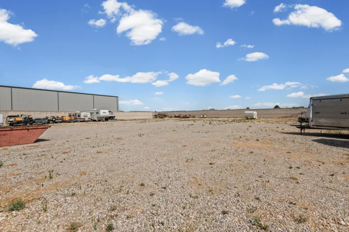 Expansive gravel lot with a large industrial building and clear sky