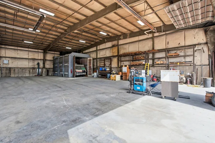 Expansive concrete flooring with high ceilings, featuring exposed metal beam construction and integrated overhead lighting