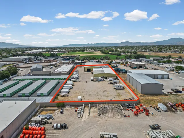 Industrial property featuring multiple buildings, expansive lot, paved and gravel surfaces, and a loading dock