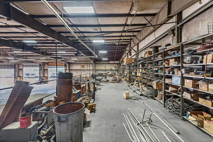 High-bay warehouse space with concrete flooring, exposed steel beam construction, and multiple roll-up doors