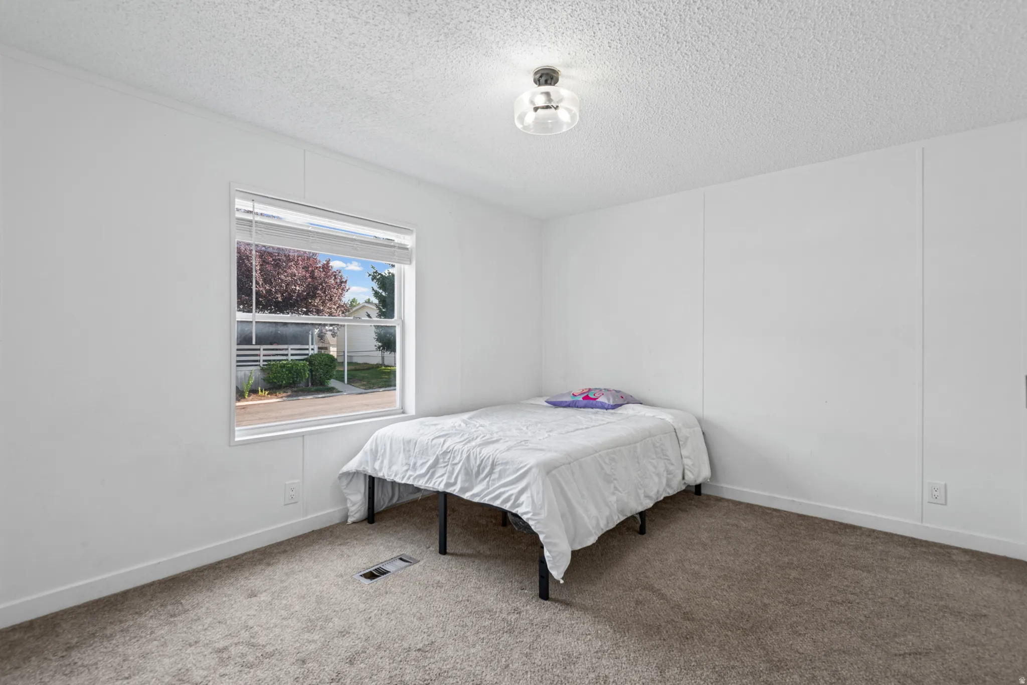 Carpeted room featuring a single window, white walls, and a flush-mount ceiling light