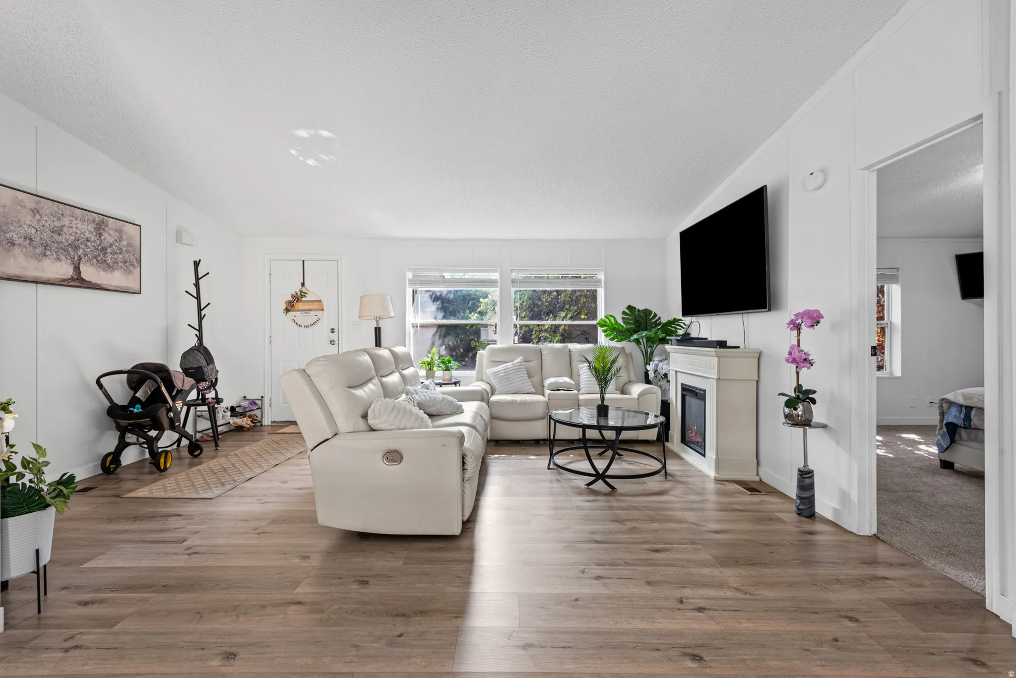 Bright living area with wood-finish flooring, multiple windows, and a built-in electric fireplace