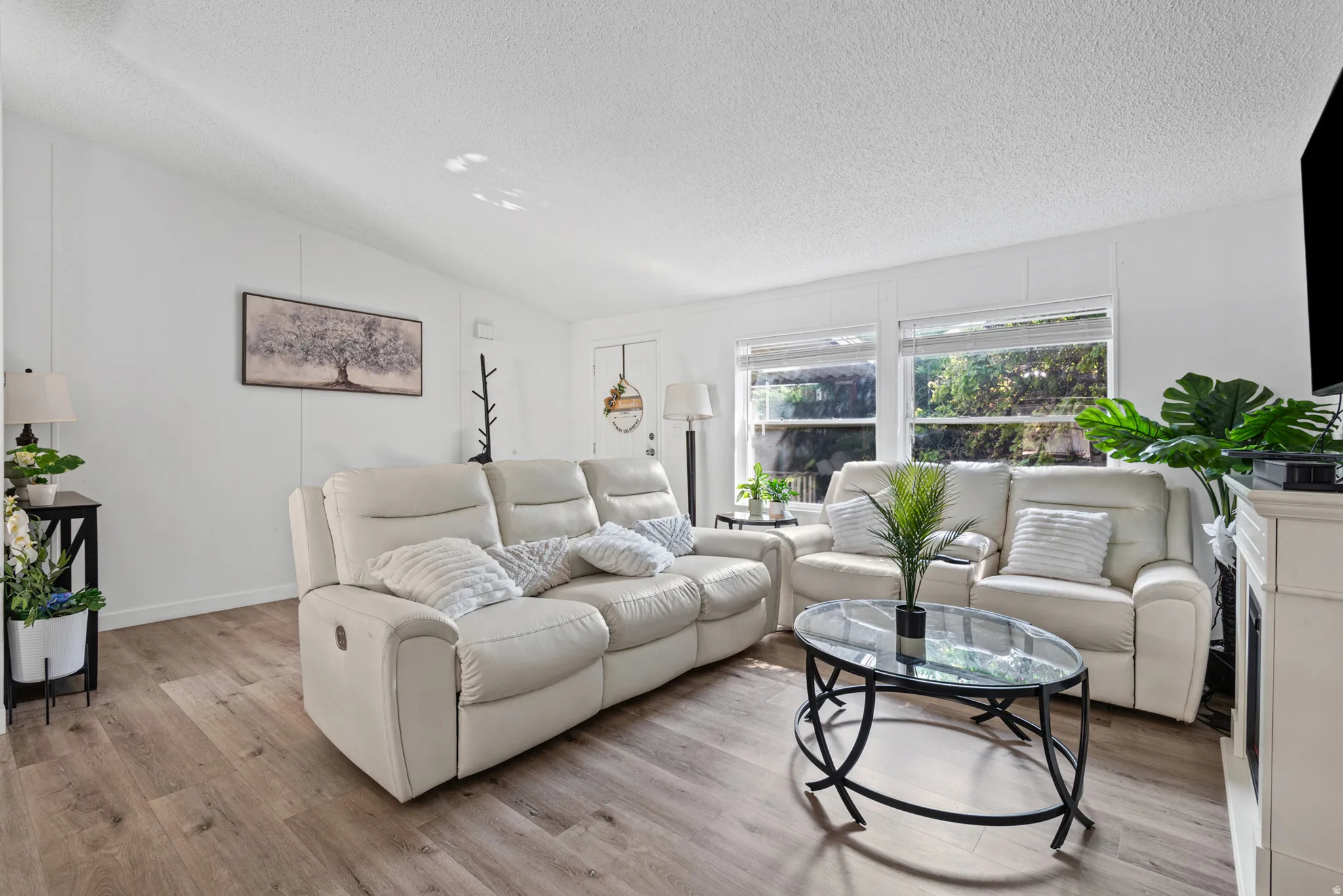 Wood-finish flooring throughout, white wall paneling, multiple windows with blinds, and recessed lighting
