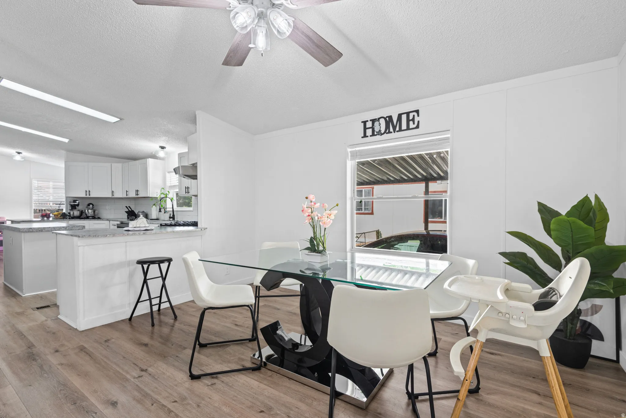 Wood-finish flooring, white walls, ceiling fan with light fixture, window with blinds, and white cabinetry