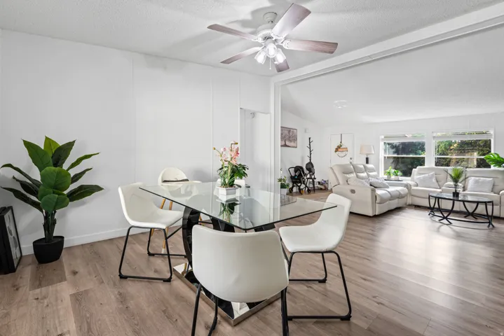 Wood-finish flooring throughout, bright white walls, and a ceiling fan with integrated lighting