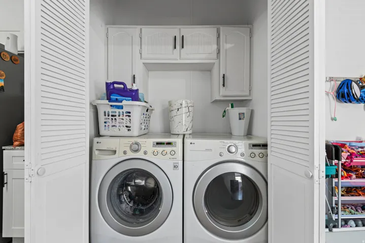 Dedicated laundry area with upper cabinetry and louvered bifold doors