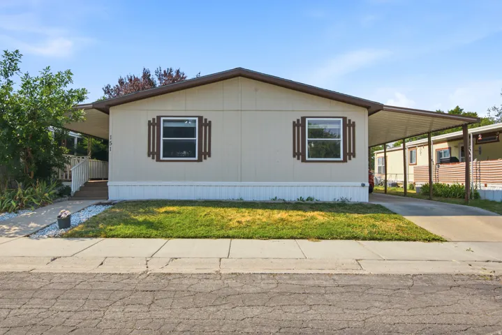 Front elevation with a covered entryway, attached carport, and a light-toned exterior with dark trim