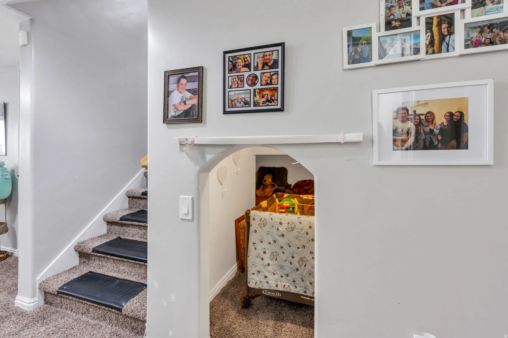 Carpeted staircase with risers, white baseboards, and a rounded archway