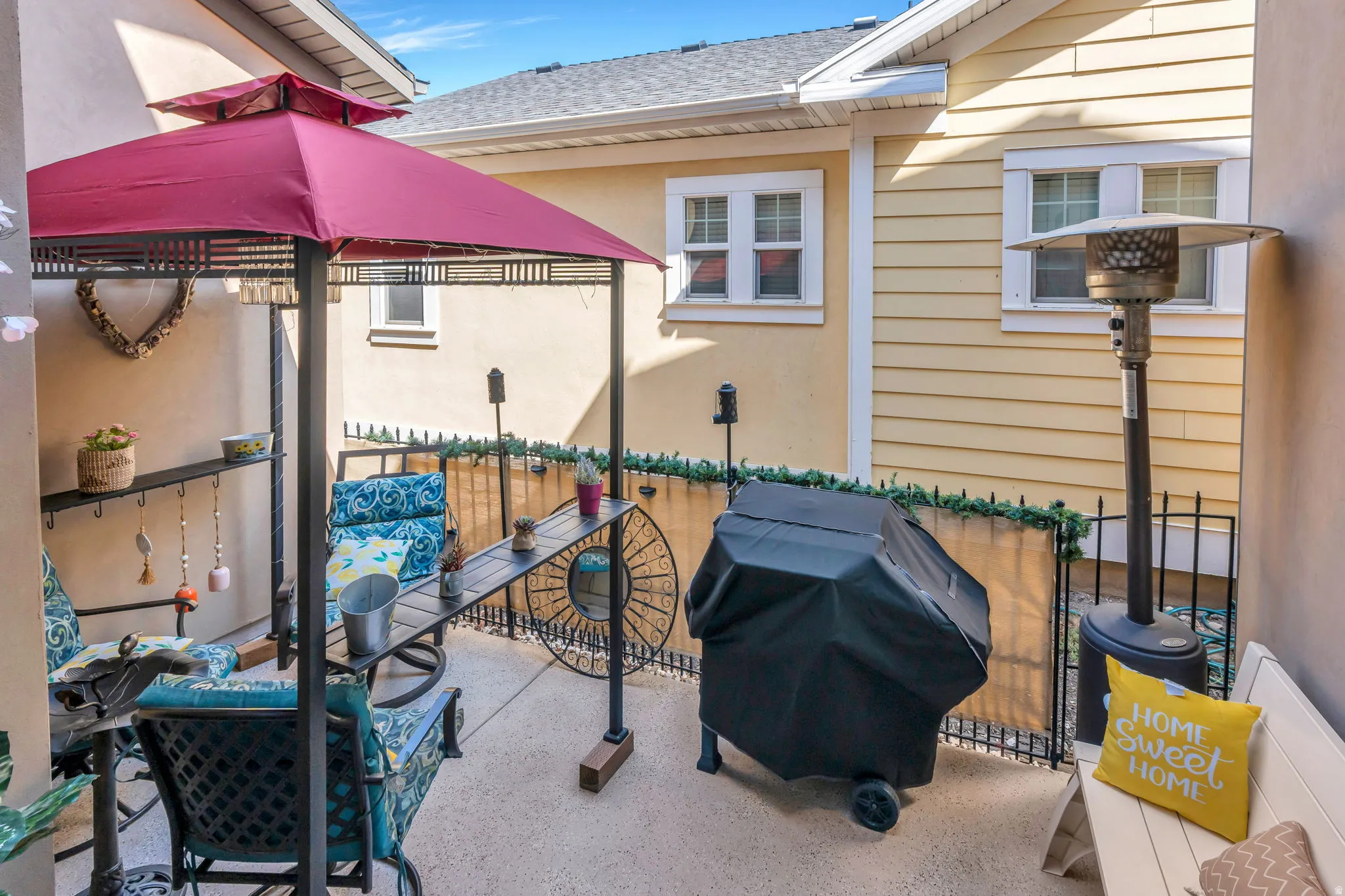 Paved patio area featuring a metal gazebo with a fabric canopy, and a privacy fence