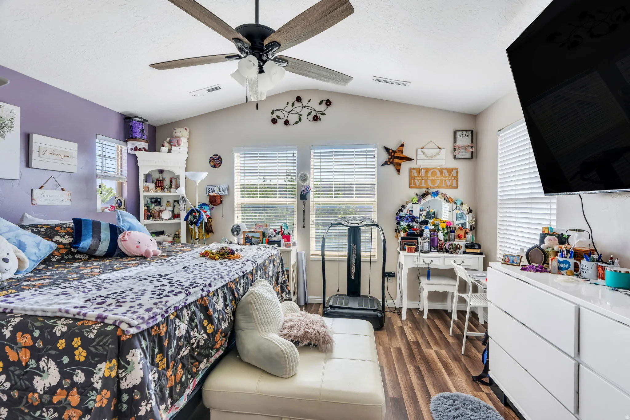 Vaulted ceiling with a ceiling fan, wood-finish flooring, and multiple windows with blinds