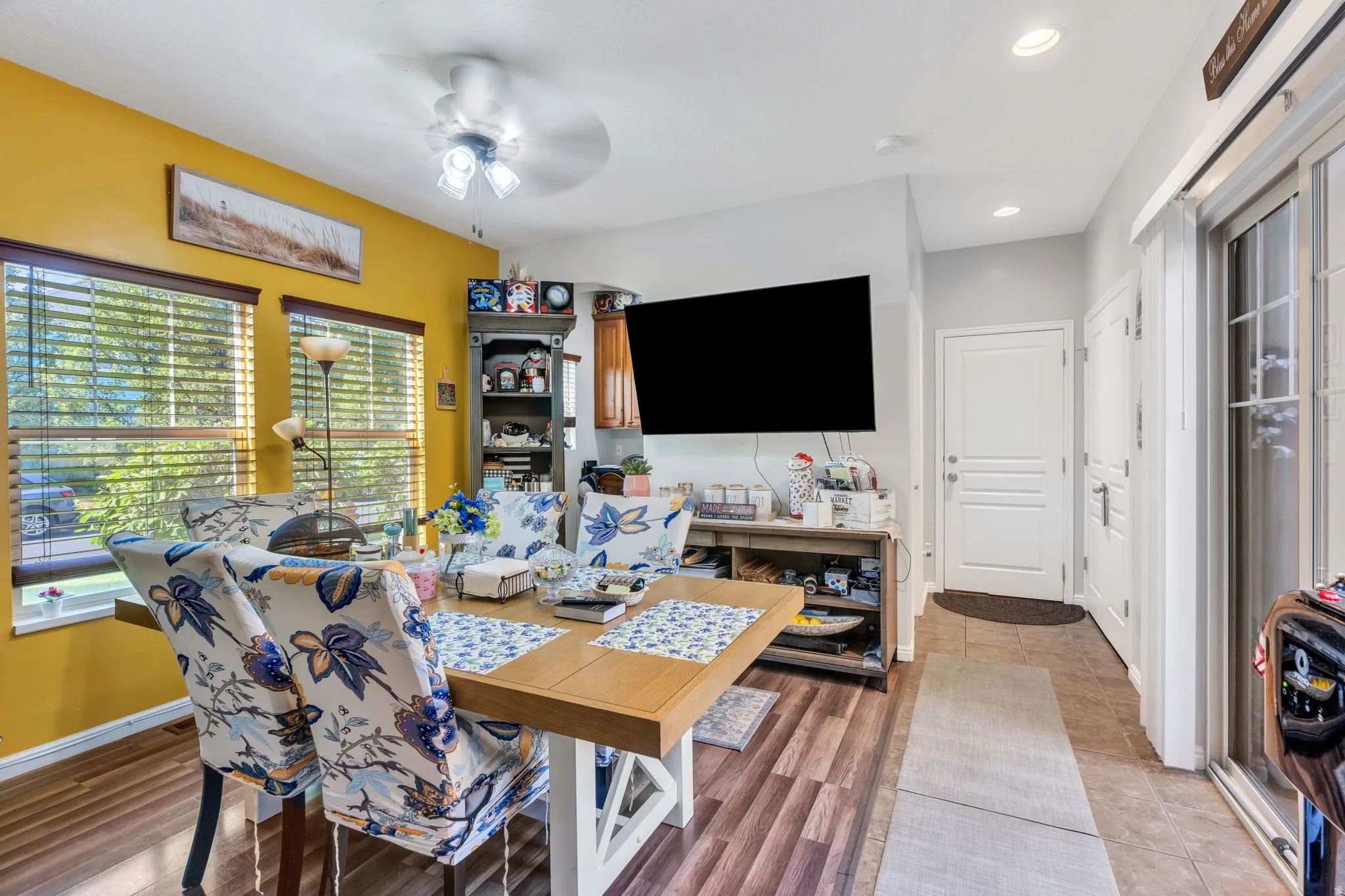 Spacious dining area featuring wood-finish flooring, ample natural light from two windows, and a ceiling fan
