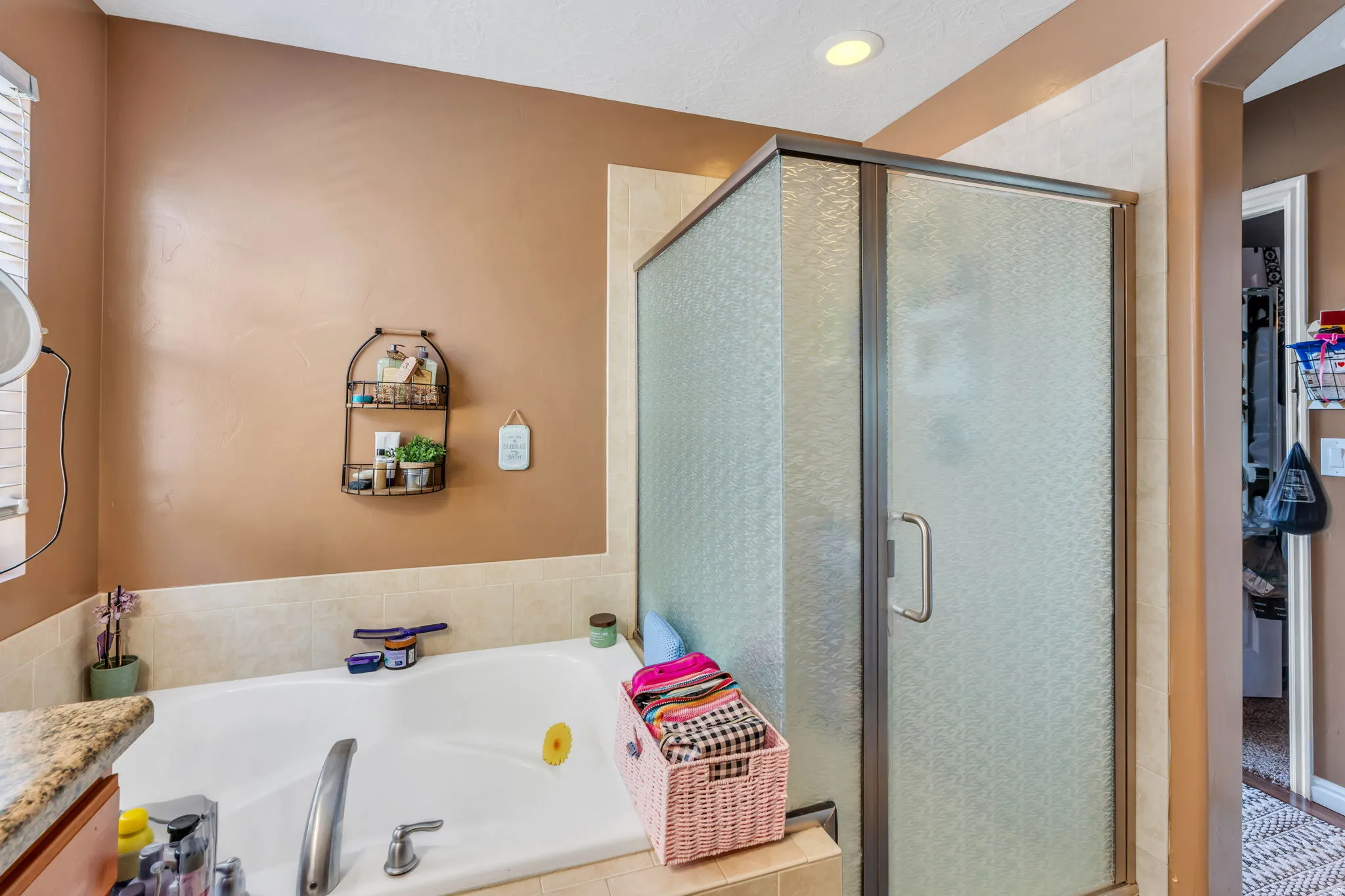 Enclosed shower with textured glass, large soaking tub, and tiled tub surround