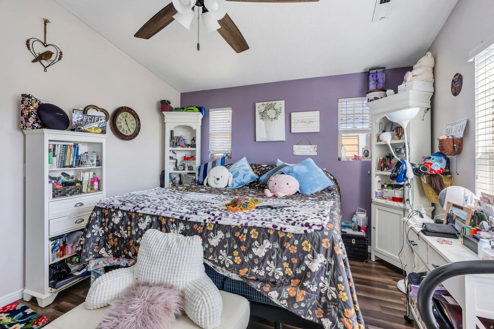 Vaulted ceiling with a ceiling fan, wood-finish flooring, and multiple windows