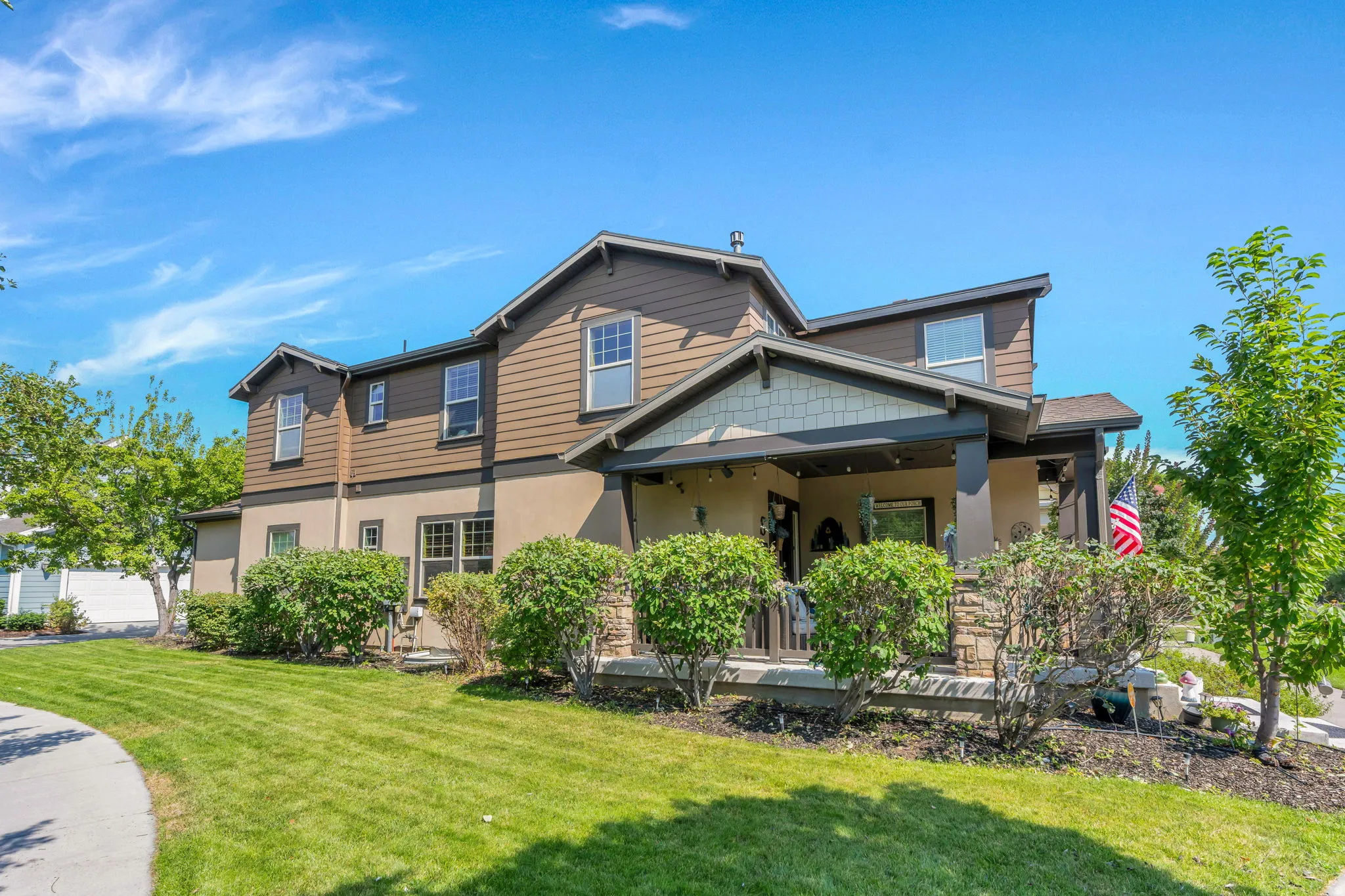 Property exterior featuring a covered porch with stone columns, horizontal siding, shake siding accents, and stucco finishes