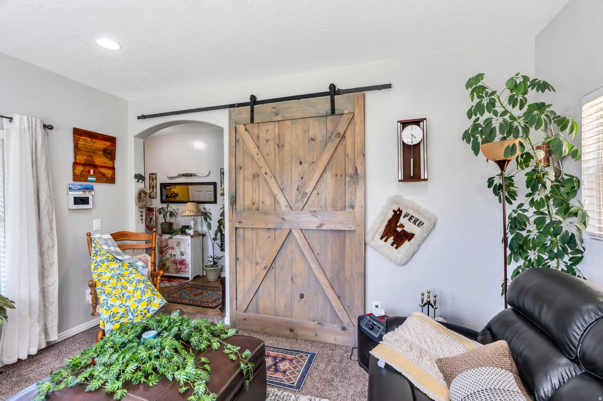 Wood-finish barn door on a black metal track, recessed ceiling lighting, and an arched doorway
