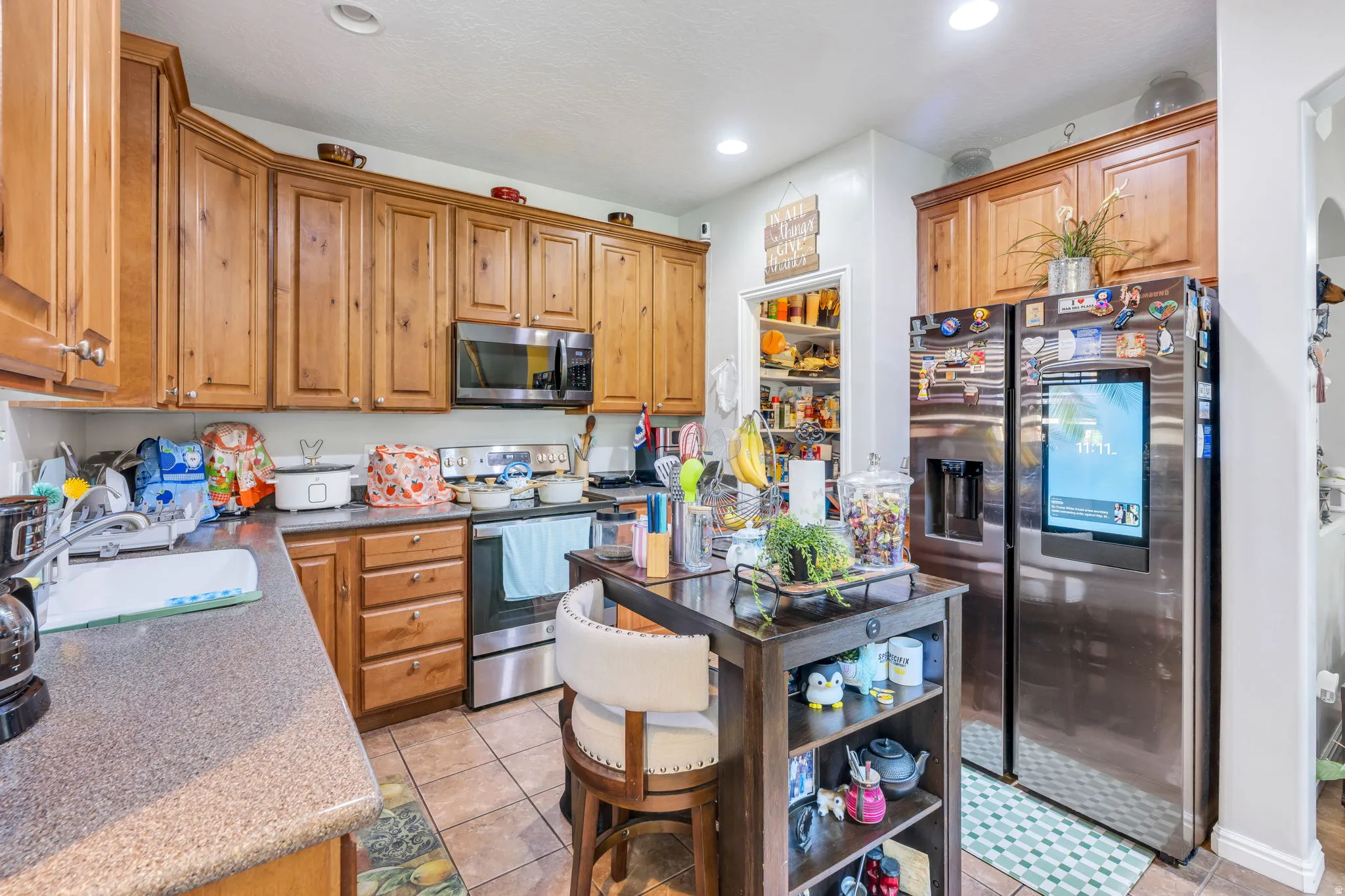 Warm wood cabinetry, stainless steel appliances, recessed lighting, and tile flooring
