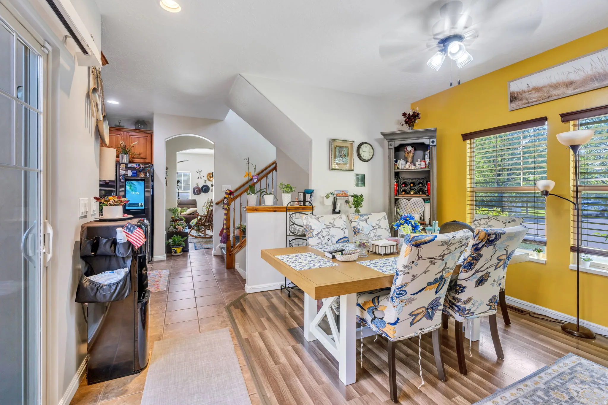 Dining area featuring wood-finish flooring, a ceiling fan with integrated lighting, and multiple windows with blinds