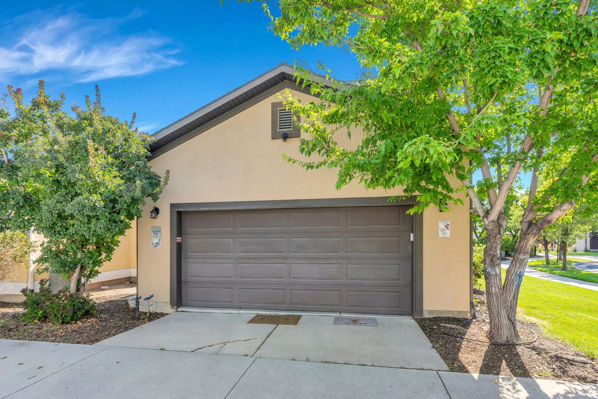 Stucco exterior with a peaked roofline, an attached garage, and a concrete driveway