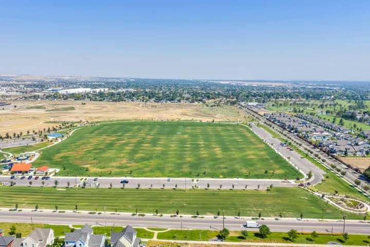 Expansive green spaces featuring a large sports field, adjacent residential area, and distant urban landscape