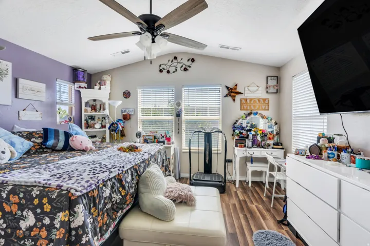 Vaulted ceiling with a ceiling fan, wood-finish flooring, and multiple windows with blinds