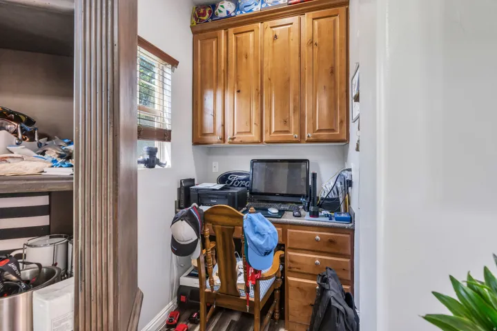 Built-in desk with wood-finish cabinetry, upper storage cabinets, and wood-finish flooring