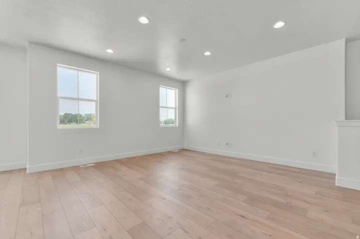 Spacious room featuring light wood-finish flooring, recessed lighting, and multiple windows