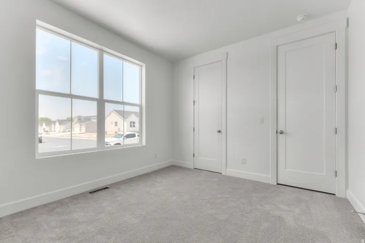 Expansive window with white trim, light gray carpeting, crisp white walls, and two paneled interior doors