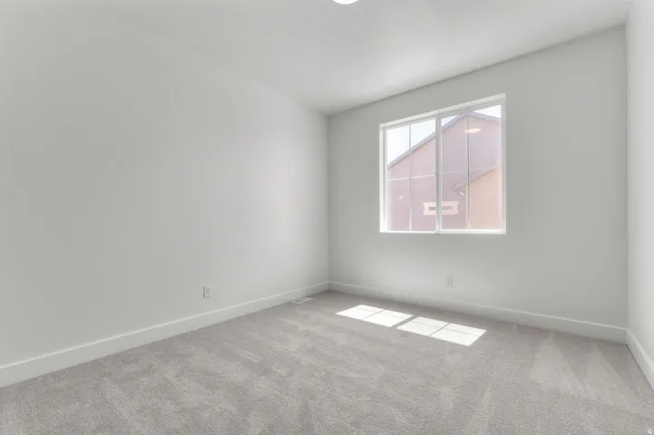 Neutral wall paint, light-colored carpeting, recessed ceiling lighting, and a multi-pane window