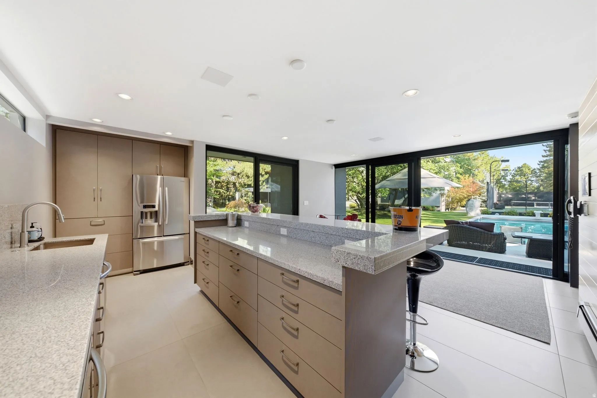 Contemporary kitchen featuring light wood-finish cabinetry, stainless steel refrigerator, and light-toned countertops